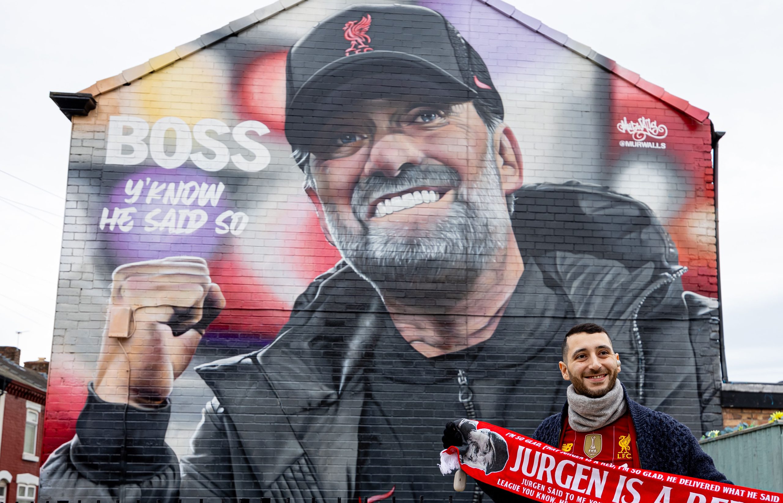 Un seguidor del Liverpool posa bajo un mural de Klopp después de anunciar su sorprendente decisión de irse